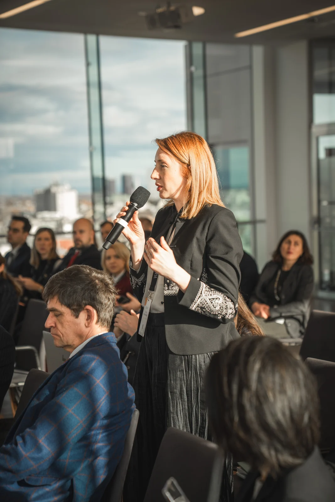 Teilnehmerin stellt mit einem Mikrofon eine Frage bei einer Konferenz