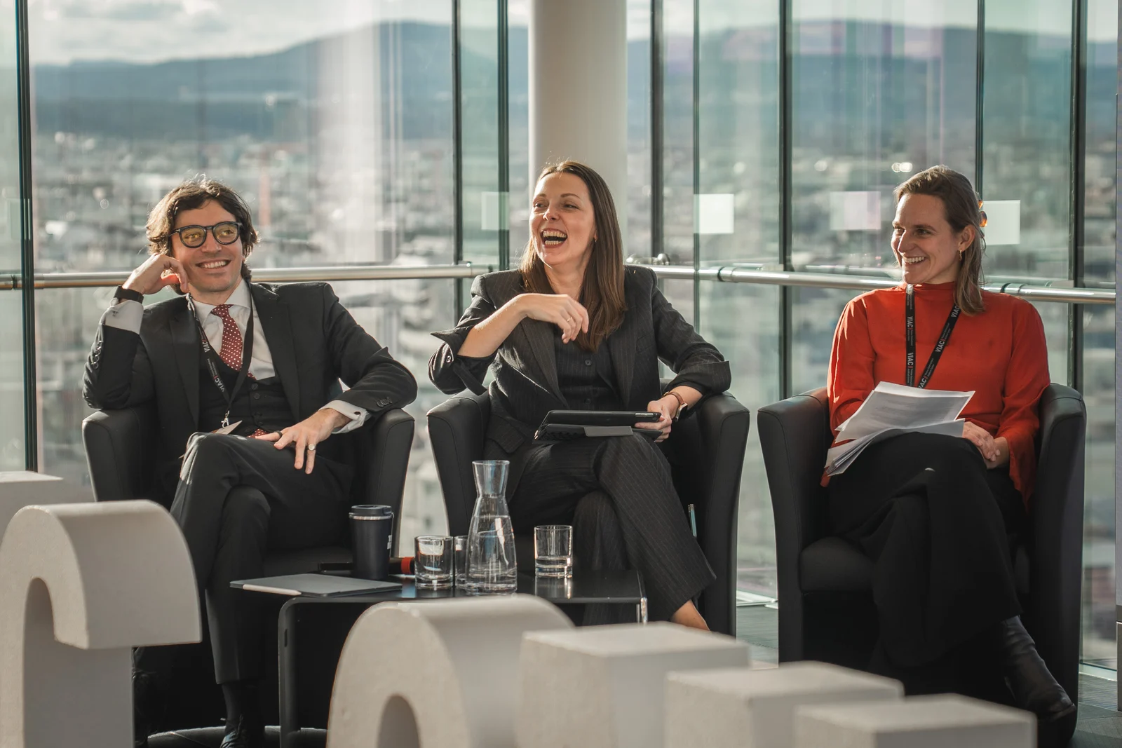 Gesprächsrunde mit drei lächelnden Teilnehmenden auf einer Konferenz